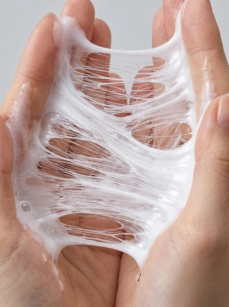 A close-up of two hands stretching a translucent, white, elastic slime-like substance with visible strands between the palms, against a light gray background.