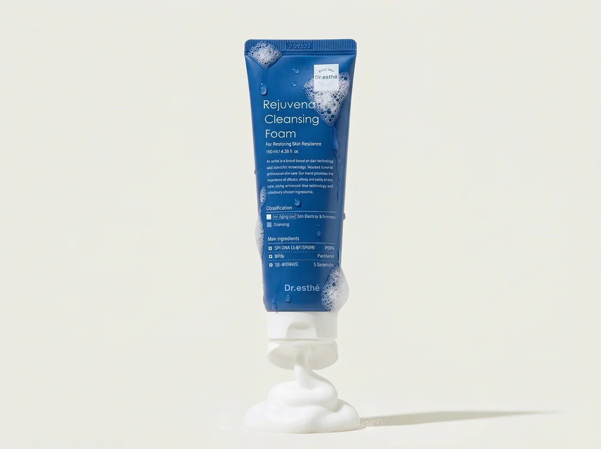 Dr. Esthel Rejuvenating Cleansing Foam in a blue squeeze tube with white foam visible at the top and bottom, set against a light beige background.